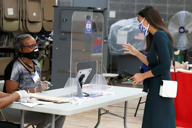 A volunteer helps U.S. Rep. Alexandria Ocasio-Cortez (D-NY), vote early in the Democratic congressional primary election, with a plastic partition for COVID-19 preventative measures, at the Justice Sonia Sotomayor Community Center in the Bronx borough of New York City, U.S., June 20, 2020. (Photo by Caitlin Ochs/Reuters)