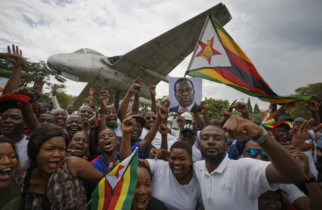 Supporters of Emmerson Mnangagwa, the man expected to become Zimbabwe's new president, hold a photograph of him and cheer as they arrive to show their support at Manyame Air Force base where Mnangagwa is expected to arrive later in the day in Harare, Zimbabwe Wednesday, November 22, 2017. Mugabe resigned as president with immediate effect Tuesday after 37 years in power, shortly after parliament began impeachment proceedings against him. (Photo by Ben Curtis/AP Photo)