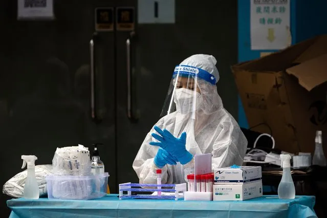 A health worker puts gloves on during Covid-19 tests of the entire population in Macau on November 1, 2022. (Photo by Eduardo Leal/AFP Photo)
