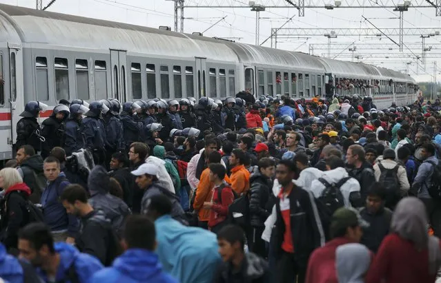 Police secure a part of a platform as migrants wait to board a train at the station in Tovarnik, Croatia, September 20, 2015. (Photo by Antonio Bronic/Reuters)