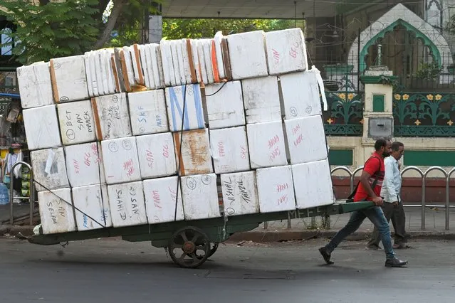 A man pulls a handcart loaded with polystyrene boxes to load fish from a market in Mumbai on November 16, 2022 (Photo by Indranil Mukherjee/AFP Photo)