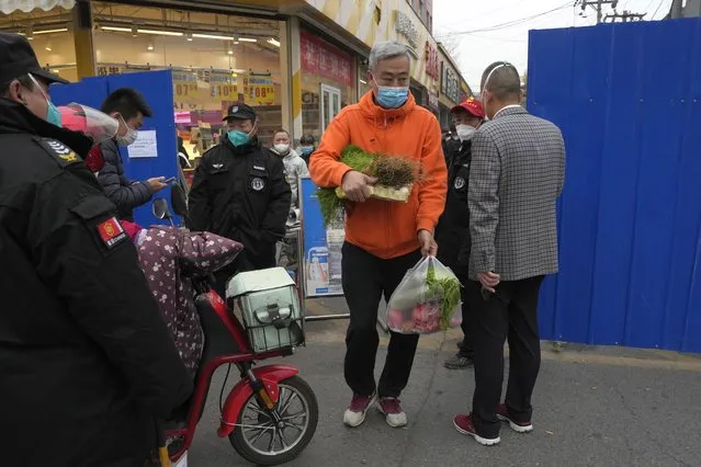 A man leaves with his grocery shopping from a community under lockdown in Beijing, Thursday, November 24, 2022. (Photo by Ng Han Guan/AP Photo)