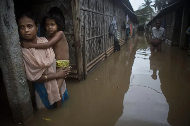 A woman holds her daughter stands awaiting her husband who went to collect drinking water after flood waters enter their house following heavy monsoon rains in Gauhati, India, Wednesday, September 23, 2015. (Photo by Anupam Nath/AP Photo)