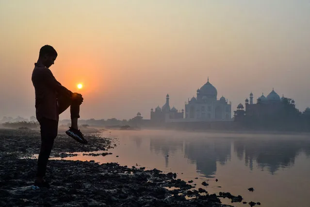 A boy exercises on the banks of the Yamuna River near the Taj Mahal in Agra at sunrise on October 17, 2022. (Photo by Pawan Sharma/AFP Photo)