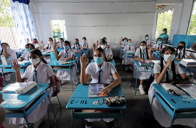 Students wearing protective face masks practice keeping a one meter distance as they attend a maths lesson inside a class room on the first day at Vidyakara college, which re-opened after almost two months of lock-down amidst concerns about the spread of coronavirus disease (COVID-19), in Colombo, Sri Lanka on July 6, 2020. (Photo by Dinuka Liyanawatte/Reuters)