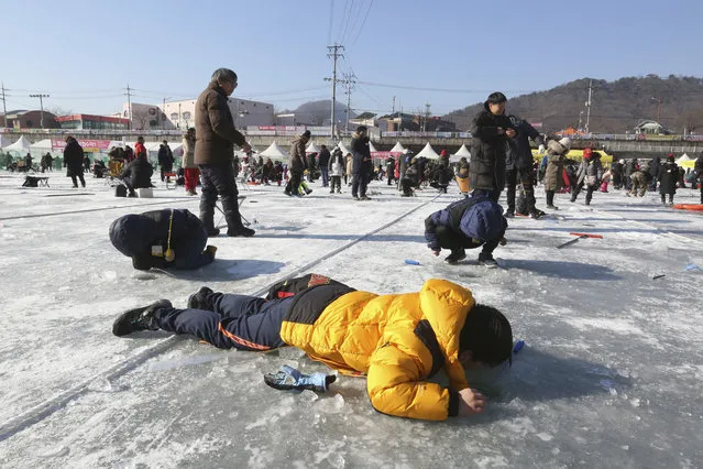A boy casts a line through a hole drilled in the surface of a frozen river during a trout catching contest in Hwacheon, South Korea, Saturday, January 6, 2018. (Photo by Ahn Young-joon/AP Photo)