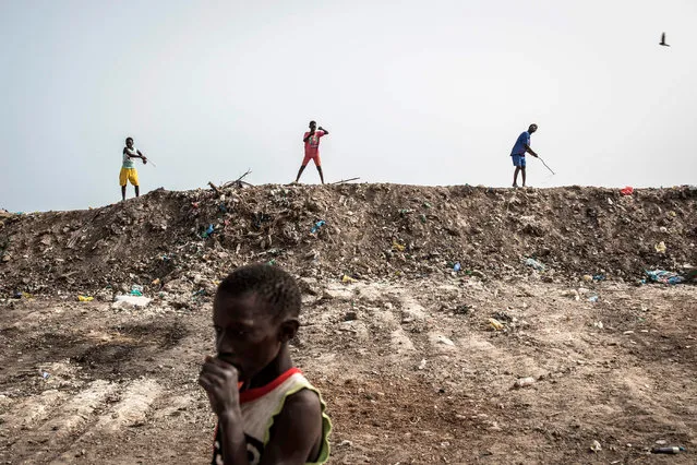 Children try to catch swallows, which are attracted by the flies in the rubbish piled along the coastline, in Bargny on July 06, 2020. The coastline of Bargny is well known for being an environmental disaster. The small fishing village caught between a cement factory, an old coal factory and hundreds of Senegalese smoking fish along the shoreline that is exported throughout West Africa. (Photo by John Wessels/AFP Photo)