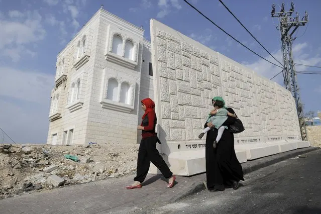 Women walk past a newly erected temporary concrete wall that measures around 10 meters in length, in the East Jerusalem neighbourhood of Jabel Mukaber October 19, 2015. (Photo by Ammar Awad/Reuters)