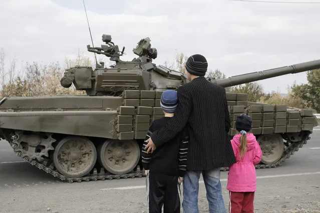 Local people look on at the Pro-Russian rebel's tank column at the Lugansk region, Ukraine, 20 October 2015. Ukraine and pro-Russian rebels continue to withdraw their guns with a caliber of less than 100 millimeters from the front line in Donetsk and Lugansk areas, in  accordance with the Minsk agreement. (Photo by Alexander Ermochenko/EPA)