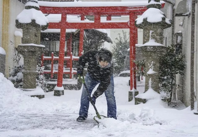 A person shovels the snow in front of a shrine Wednesday January 25, 2023 in Tottori, Tottori Prefecture, western Japan. Snow and cold weather were affecting much of Japan on Wednesday, disrupting highway, air and train travel, and more snow and cold temperatures were forecast. (Photo by Kyodo News via AP Photo)