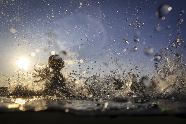 A young woman jumps into the river Rhine to cool off during high temperatures, near Kaiserstuhl, Switzerland, Sunday, June 22, 2025. (Photo by Michael Buholzer/Keystone via AP Photo)