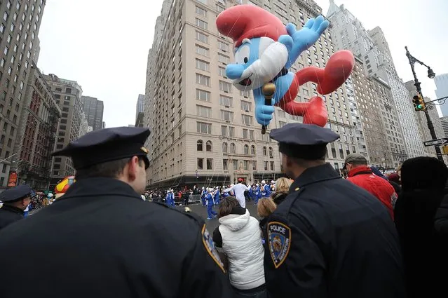 Police officers watch as the Papa Smurf Balloon floats at the 88th Annual Macy's Thanksgiving Day on November 27, 2014 in New York City. (Photo by Brad Barket/Getty Images)