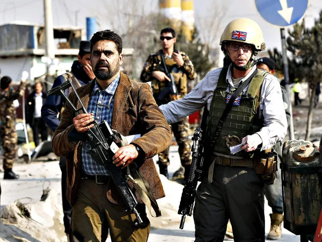 A British security official (R) escorts a survivor from the wreckage of a British embassy vehicle after a suicide attack in Kabul, November 27, 2014. (Photo by Omar Sobhani/Reuters)