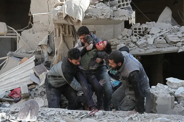 Syrians rescue a child following a reported regime air strike in the rebel-held town of Hamouria, in the besieged Eastern Ghouta region on the outskirts of the capital Damascus on February 21, 2018. (Photo by Abdulmonam Eassa/AFP Photo)