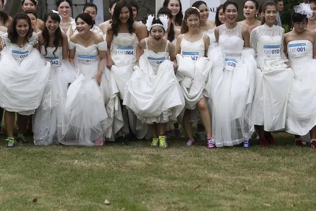 Brides-to-be get ready for the “Running of the Brides” race in a park in Bangkok November 29, 2014. Seventy-five husbands and wives-to-be wore their wedding dresses and running shoes and competed in an event for a combined prize worth 1 million Thai baht ($30,460). (Photo by Damir Sagolj/Reuters)