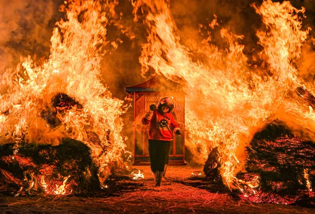 A villager walks from a fire carrying a chair during traditional folk activity to celebrate the Lantern Festival on February 6, 2023 in Huian County, Quanzhou City, Fujian Province of China. (Photo by Ye Xiaofeng/VCG via Getty Images)