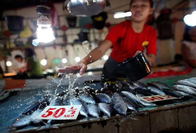 A vendor sprinkles water over fish for sale as she waits for customers inside a public market in Las Pinas, south of Metro Manila November 5, 2009. (Photo by John Javellana/Reuters)