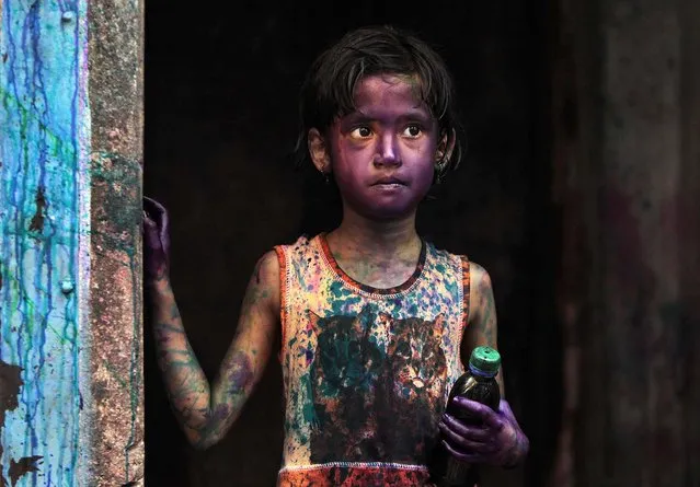 A child smeared in colors stands at a doorway during Holi festival celebrations in Dhaka, Bangladesh, on March 28, 2013. Hindus celebrate Holi, the festival of colors, by painting each other in bright pigments, distributing sweets and squirting water at one another. The holiday celebrated mainly in India and Nepal marks the beginning of spring and the triumph of good over evil. (Photo by A.M. Ahad/Associated Press)