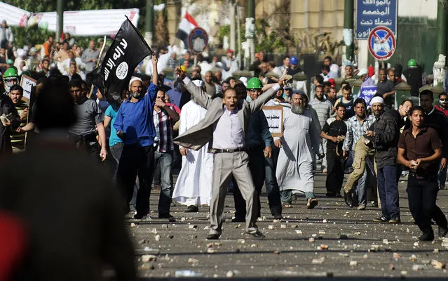 A protester gestures in front of an islamic flag during clashes between the Muslim Brotherhood movement's opponents and supporters on April 19, 2013 in central Cairo. Two people were hurt after anti-Islamist protesters marched on thousands of Islamists who had rallied outside the Supreme Court in central Cairo demanding judicial reform. (Photo by Gianluigi Guercia/AFP Photo)