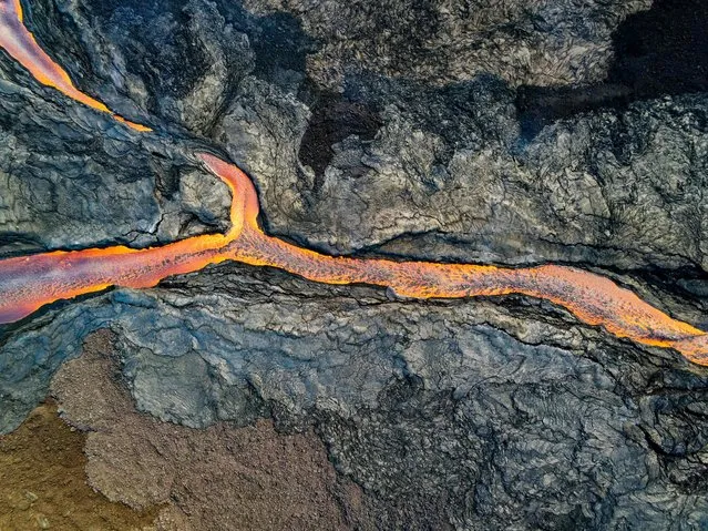 In this handout photo from the US Geological Survey taken on December 4 and obtained on December 6, 2022, an aerial view shows the fissure 3 lava channel erupting from Mauna Loa's Northeast Rift Zone at the Mauna Loa Volcano near Hilo, Hawaii. The world's largest active volcano burst into life for the first time in 40 years, spewing lava and hot ash since November 28, 2022, in a spectacular display of nature's fury by Mauna Loa in Hawaii. Rivers of molten rock could be seen high up on the volcano, venting huge clouds of steam and smoke at the summit on Big Island, and sparking warnings the situation could change rapidly. (Photo by USGS/US Geological Survey/AFP Photo)