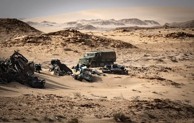 A Moroccan army vehicles drives past car wreckages in Guerguerat located in the Western Sahara, on November 24, 2020, after the intervention of the royal Moroccan armed forces in the area. Morocco in early November accused the Polisario Front of blocking the key highway for trade with the rest of Africa, and launched a military operation to reopen it. (Photo by Fadel Senna/AFP Photo)