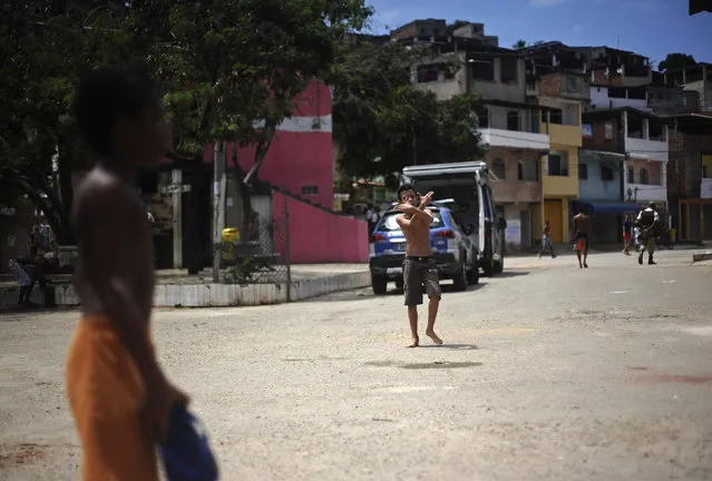 A boy plays on the street of the Nordeste de Amaralina slum complex in Salvador, Bahia State, March 28, 2013. One of Brazil's main tourist destinations and a 2014 World Cup host city, Salvador suffers from an unprecedented wave of violence with an increase of over 250% in the murder rate, according to the Brazilian Center for Latin American Studies (CEBELA). Picture taken March 28, 2013. (Photo by Lunae Parracho/Reuters)