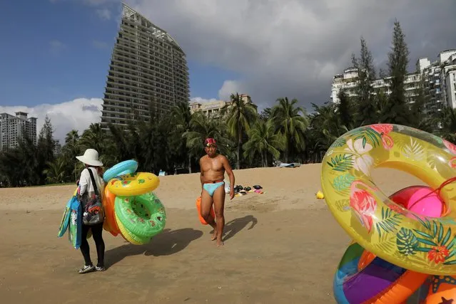 Vendors selling swimming accessories walk on Sanya Bay beach in Sanya, Hainan province, China on November 26, 2020. (Photo by Tingshu Wang/Reuters)