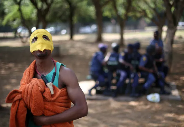 A protester wearing a mask gestures infront of riot police officers during a march to South African President Jacob Zuma's offices, to demand free university education, in Pretoria, South Africa,October 20, 2016. (Photo by Siphiwe Sibeko/Reuters)