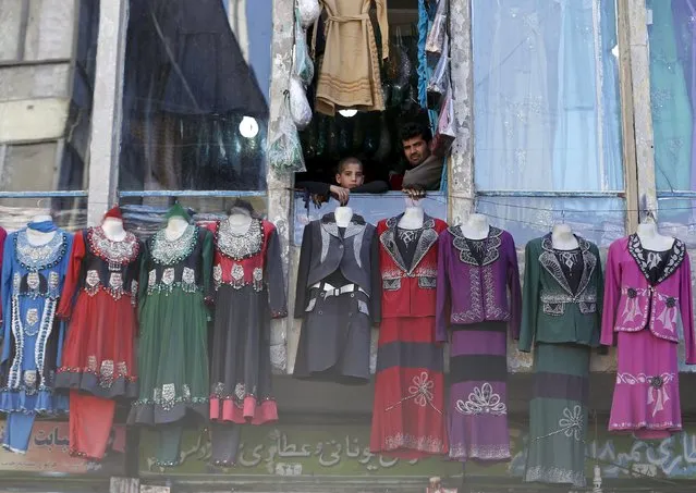 An Afghan shopkeeper waits for customers with his son at his shop which sells female clothing, ahead of the Eid al-Adha festival, in Kabul, Afghanistan September 23, 2015. (Photo by Omar Sobhani/Reuters)
