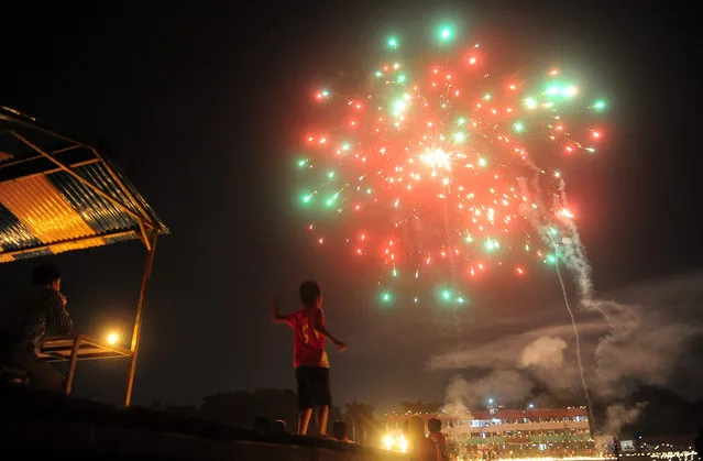 In this photograph taken on October 29, 2016, an Indian child watches fireworks at the Madan Mohan Malviya stadium on the eve of the Hindu festival of Diwali in Allahabad. Diwali, the Festival of Lights, marks victory over evil and commemorates the time when Hindu god Lord Rama achieved victory over Ravana and returned to his kingdom Ayodhya. (Photo by Sanjay Kanojia/AFP Photo)