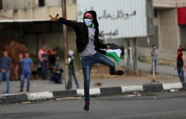 A Palestinian protester uses a sling shot to hurl stones at Israeli troops during clashes at Hawara checkpoint near the West Bank city of Nablus November 28, 2015. (Photo by Ahmad Talat/Reuters)