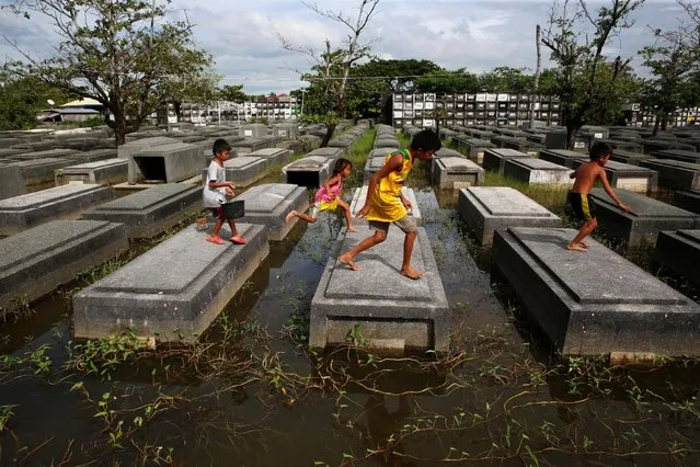 Residents who work at a cemetery to refurbish tombs ahead of the commemoration of All Saints Day, walk on tombs in a flooded cemetery at Masantol, Pampanga in northern Philippines, October 26, 2016. (Photo by Erik De Castro/Reuters)