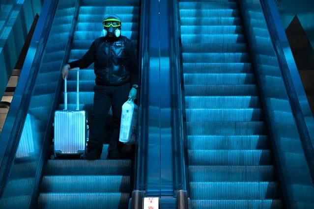 A traveler wearing a mask to protect against the spread of the coronavirus rides an escalator beneath a colored skylight at the Beijing Railway Station in Beijing, Thursday, January 28, 2021. Efforts to dissuade Chinese from traveling for Lunar New Year appeared to be working. Beijing's main train station was largely quiet on the first day of the travel rush and estimates of passenger totals were smaller than in past years. (Photo by Mark Schiefelbein/AP Photo)