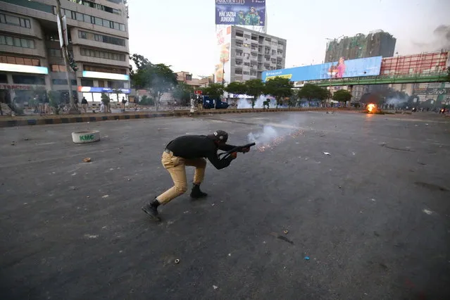 A police officer fires a gas launcher as supporters of Pakistan's former Prime Minister Imran Khan clash with police during a protest against Khan's arrest, in Karachi, Pakistan, 09 May 2023. (Photo by Shahzaib Akber/EPA)
