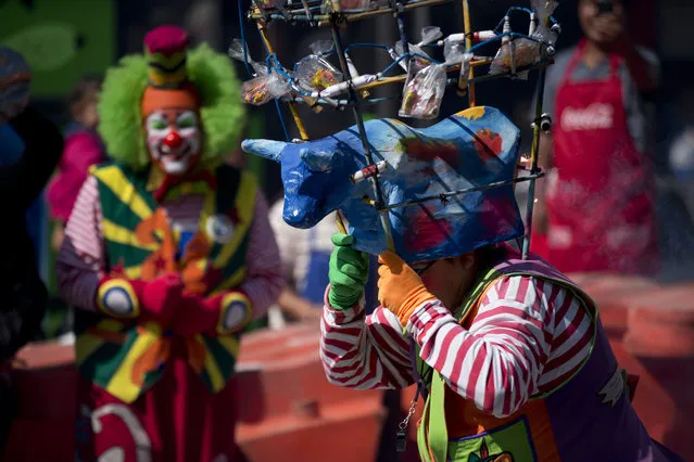 A clown runs carrying a bull headdress adorned with firecrackers, as clowns march in procession toward the Basilica of Our Lady of Guadalupe in Mexico City, Monday, December 14, 2015. (Photo by Rebecca Blackwell/AP Photo)