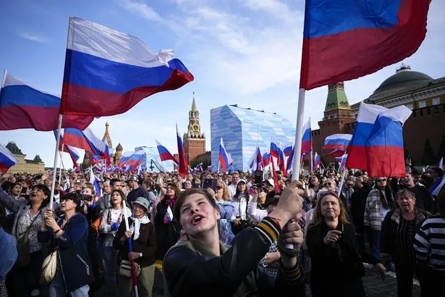 Thousands of people wave Russian national flags as they gather on Red Square to watch a concert dedicated to the Day of Russia in Moscow, Russia, Sunday, June 11, 2023. The Day of Russia is celebrated annually on 12 June. (Photo by Alexander Zemlianichenko/AP Photo)