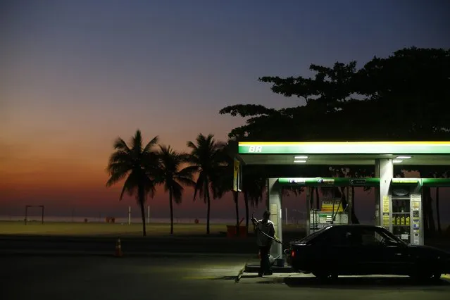 A worker prepares to fill a car at a gas station close to Copacabana beach in Rio de Janeiro, January 12, 2015. (Photo by Ricardo Moraes/Reuters)