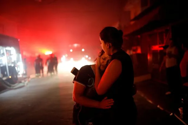 Amanda Soares, 21, hugs her mother Celia Ferro, 62, after evacuating their house following a fire that broke out at a household items warehouse in Guarulhos, on the outskirts of Sao Paulo, Brazil on April 27, 2022. (Photo by Amanda Perobelli/Reuters)