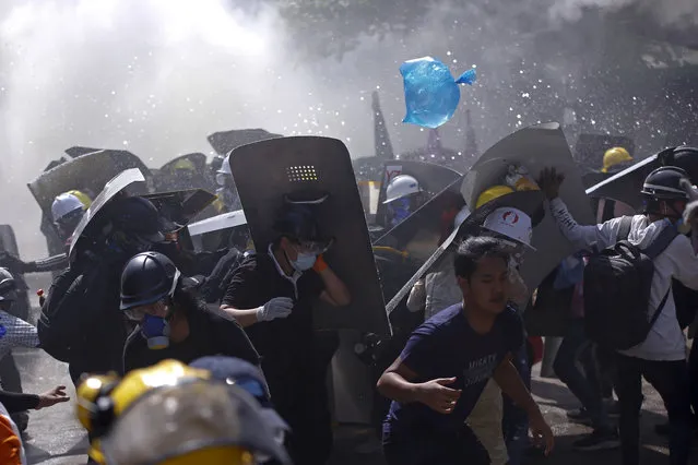 Protesters are dispersed as riot police fire tear gas during a demonstration in Yangon, Myanmar, Monday, March 8, 2021. (Photo by AP Photo/Stringer)