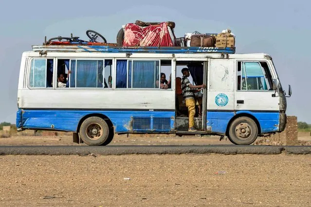 A bus carrying passengers and luggage moves along a road from Khartoum to Wad Madani at the locality of Kamlin, about 80 kilometres southeast of Khartoum, on June 22, 2023. (Photo by AFP Photo/Stringer)
