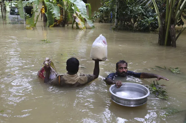 An Indian policeman, left, and a volunteer carry essential supplies for stranded people in a flooded area in Chengannur in the southern state of Kerala, India, Sunday, August 19, 2018. Some 800,000 people have been displaced and over 350 have died in the worst flooding in a century. (Photo by Aijaz Rahi/AP Photo)