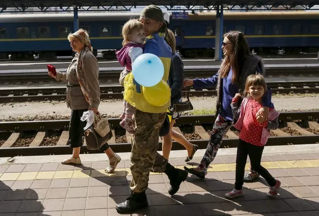 A Ukrainian serviceman carries his child after returning from the frontline in the eastern regions, as his relatives walk nearby, at a railway station in Kiev, Ukraine, September 9, 2015. (Photo by Gleb Garanich/Reuters)