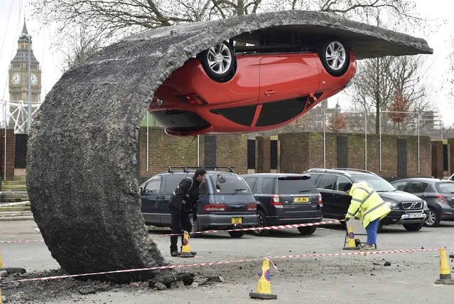 Workers move bollards near an upside down car art installation in a car park on the South Bank in London, February 19, 2015. (Photo by Toby Melville/Reuters)