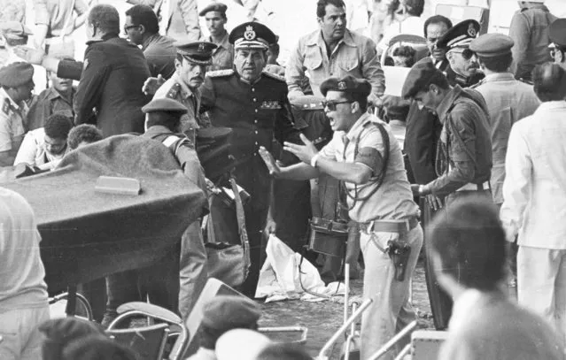In this October 6, 1981 file photo, an Egyptian security guard screams at people as medics bring in a stretcher to carry the wounded after the attack which killed President Anwar Sadat, as he watched a military parade. Shocking footage of the brazen assassination, payback for Sadat's signing a peace deal with Israel, was broadcast around the world. It also became an early propaganda trophy for Islamic radicals who had penetrated the military to carry out a cleric's order that Sadat be killed. (Photo by AP Photo)