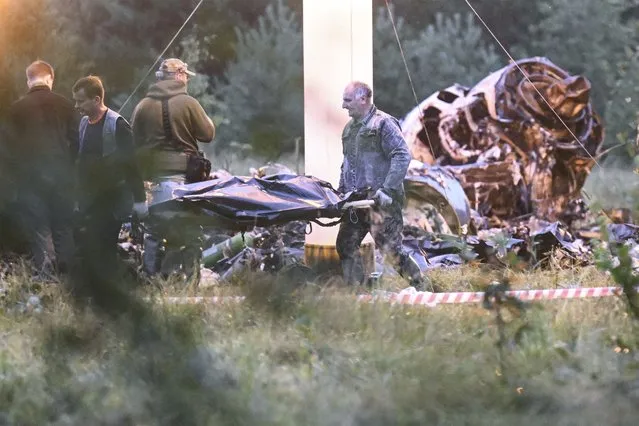 People carry a body bag away from the wreckage of a crashed private jet, near the village of Kuzhenkino, Tver region, Russia, Thursday, August 24, 2023. Russian mercenary leader Yevgeny Prigozhin, the founder of the Wagner Group, reportedly died when a private jet he was said to be on crashed on Aug. 23, 2023, killing all 10 people on board. (Photo by AP Photo/Stringer)