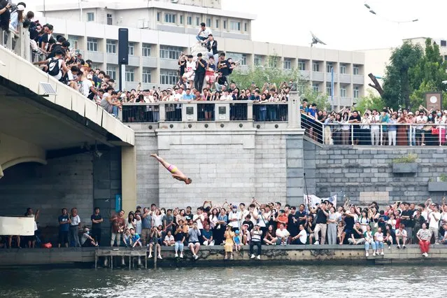 Citizens watch as an elderly man dives into the Haihe River on August 27, 2023 in Tianjin, China. (Photo by Cheng Xuliang/VCG via Getty Images)