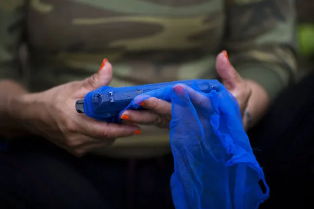 In this January 5, 2016 photo, Cindy, a rebel fighter for the 36th Front of the Revolutionary Armed Forces of Colombia, or FARC, wraps her gun in a mesh fabric, after a routine cleaning, as protection from humidity and rain, in a hidden camp in Antioquia state, in the northwest Andes of Colombia. Cindy is a field medic and she joined the guerrilla group when she was 18-years-old. “If there is peace with the government, we will have to take up politics, teach the people and later reunite with family after so many years”, she said. (Photo by Rodrigo Abd/AP Photo)