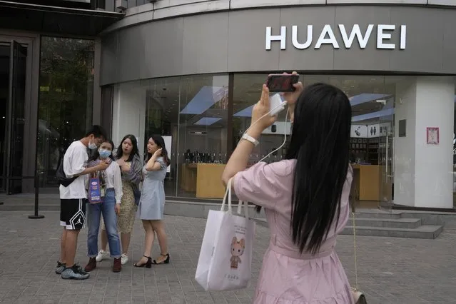 Shoppers stand outside a Huawei store in Beijing on Wednesday, June 2, 2021. Huawei is launching its own HarmonyOS mobile operating system on its handsets as it adapts to losing access to Google mobile services two years ago after the U.S. put the Chinese telecommunications company on a trade blacklist. (Photo by Ng Han Guan/AP Photo)