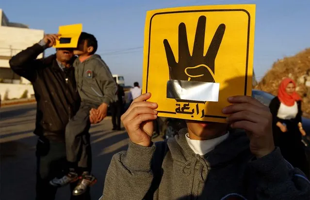 People shield their faces with specially-constructed cards showing the four-finger symbol of Rabaa, to show their support for ousted Egyptian President Mohamed Mursi, as they observe a solar eclipse in Amman, Jordan. (Photo by Muhammad Hamed/Reuters)