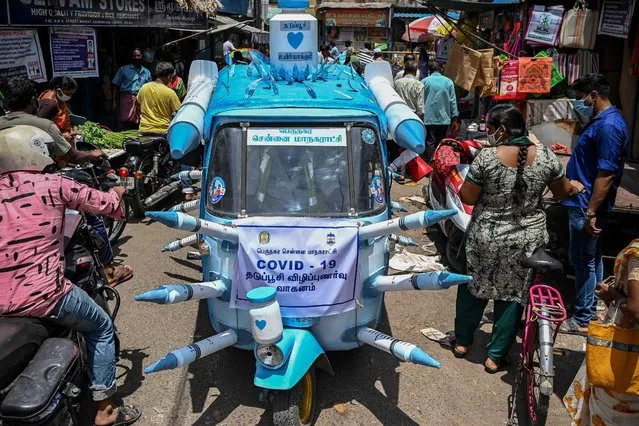 A municipal worker drives an auto-rickshaw decorated with mock syringes through the streets to boost awareness amid people on the importance of Covid-19 coronavirus vaccination in Chennai on July 3, 2021. (Photo by Arun Sankar/AFP Photo)